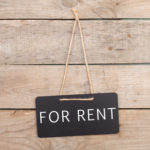 For-rent-sign-hanging-on-wood-wall