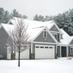 Grey single storey home in winter with tree in front