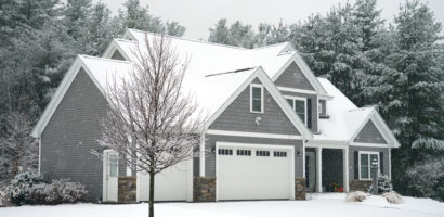 Grey single storey home in winter with tree in front