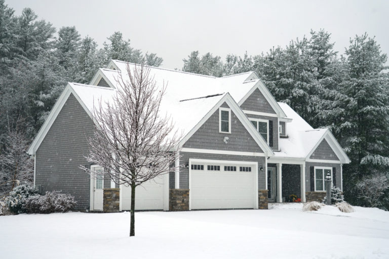 Grey single storey home in winter with tree in front