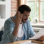 Condo owner reacts to a special assessment notice while reviewing documents at home