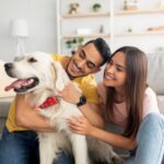 Couple sitting on the floor at home while petting their dog