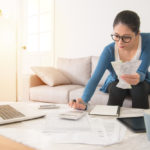 woman sitting on couch organizing receipts