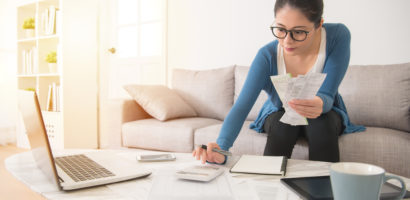 woman sitting on couch organizing receipts