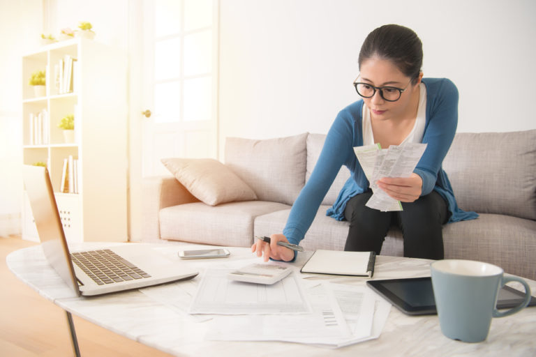 woman sitting on couch organizing receipts