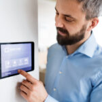 A man pointing to a tablet with smart home screen at home.