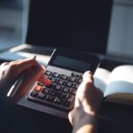 Person using a calculator while reviewing financial documents at a desk