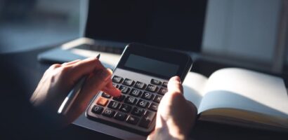 Person using a calculator while reviewing financial documents at a desk