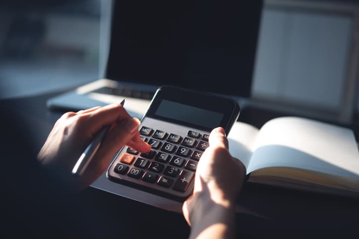 Person using a calculator while reviewing financial documents at a desk