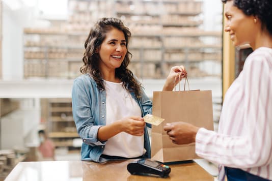 Customer pays with a credit card while receiving a shopping bag at the counter