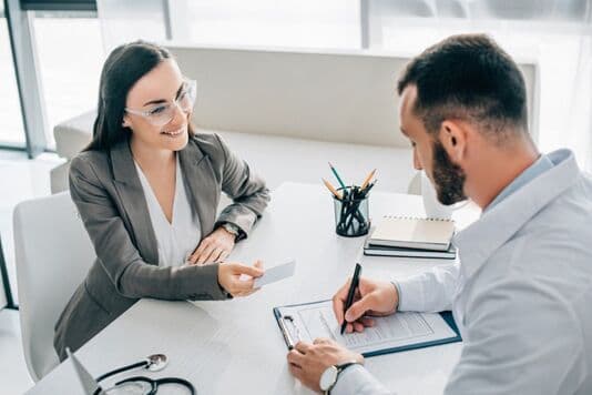 Insurance agent helps a client complete paperwork during a consultation